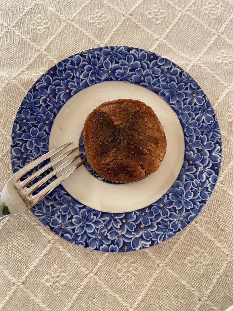 Un fico Girotti disposto su un piatto di ceramica decorato in blu, con una forchetta accanto.