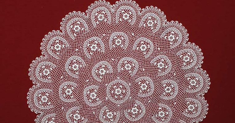 Dettaglio ravvicinato di un ricamo finemente realizzato, caratterizzato da una delicata struttura a semicerchio