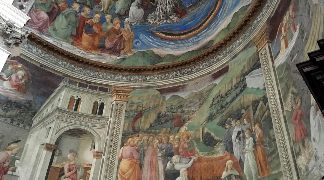 Affreschi rinascimentali nell'abside della Cattedrale di Spoleto, con scene bibliche dettagliate, architetture dipinte e paesaggi collinari.