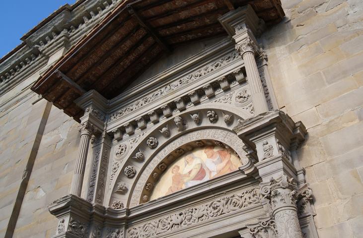 Detail of the front portal adorned with bas-reliefs and a small colonnade, featuring sculpted artworks.