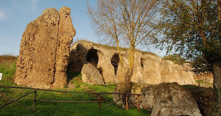 Vestiges monumentaux des grandes substructures d’Ocriculum, avec des arcades taillées dans la roche et de la végétation autour