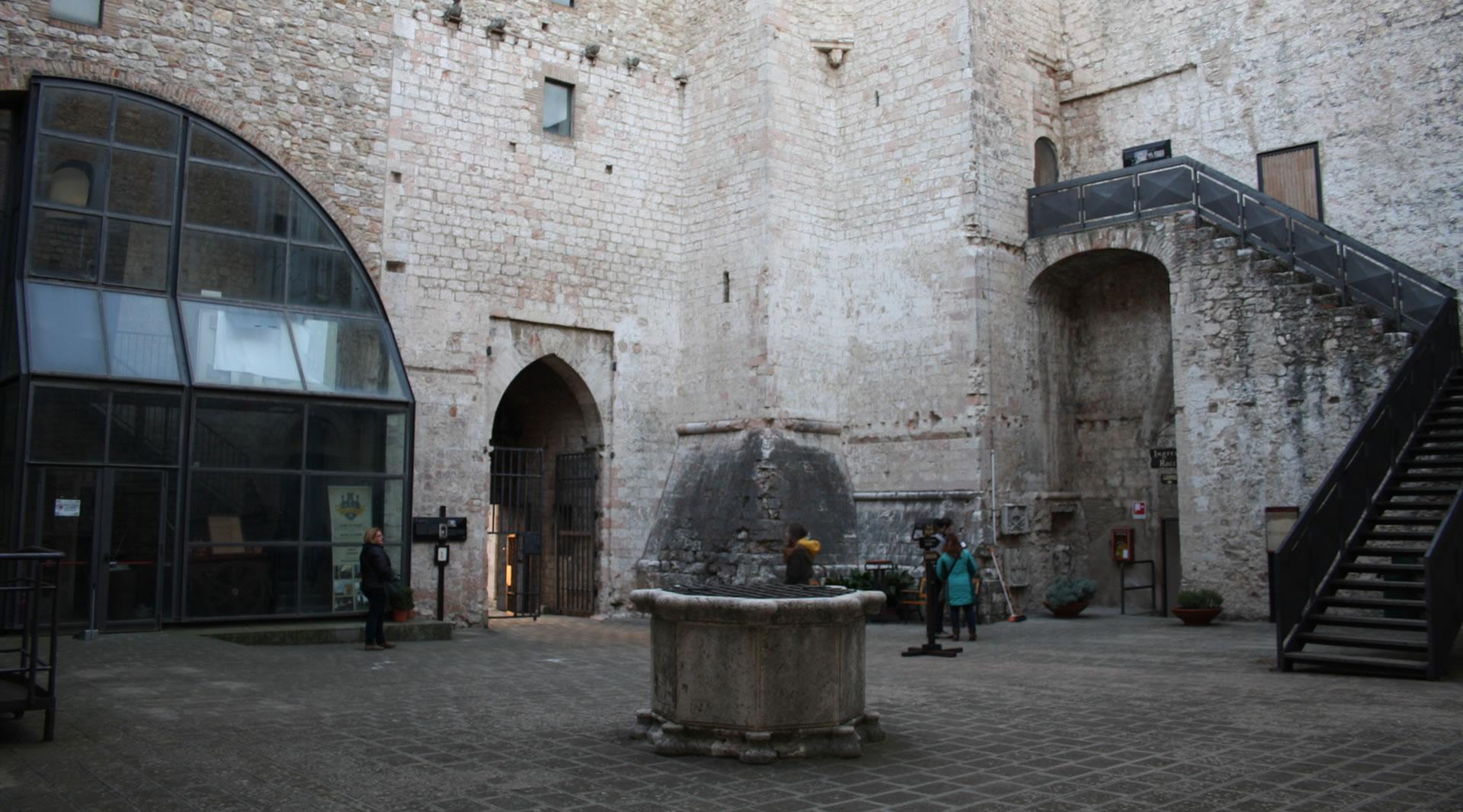 The inner courtyard of the Fortress of Narni, with its central well, medieval walls and stone access stairs.