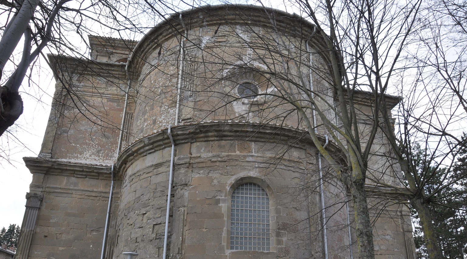 Façade arrière du Sanctuaire de la Madonna dei Miracoli, caractérisée par une grande fenêtre centrale et un puits de lumière placé en haut, permettant à la lumière naturelle d'entrer dans le bâtiment.