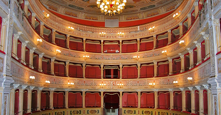 Interno del Teatro Caio Melisso di Spoleto: palchi rossi, stucchi decorati, lampadari e soffitto affrescato.