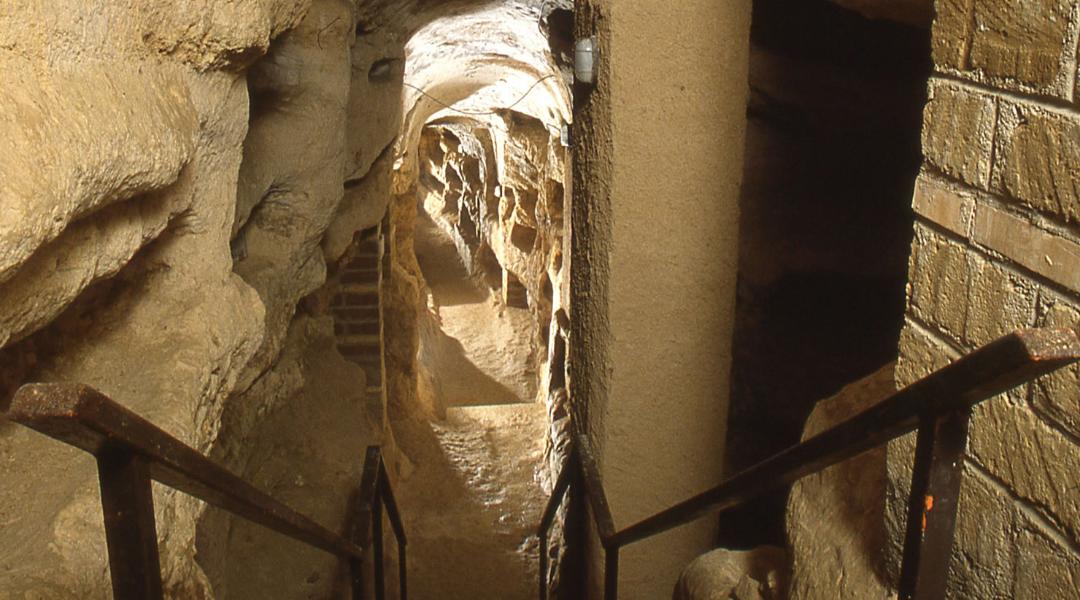 Corridoio sotterraneo all'interno della catacomba di Villa San Faustino. Lungo le pareti del corridoio, costruite con una combinazione di mattoni e pietra, si possono vedere diversi loculi, o nicchie funerarie, sovrapposti.
