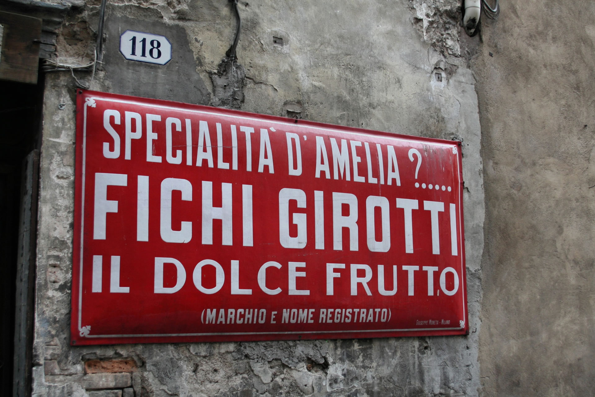 Historic red sign of Fichi Girotti in Amelia