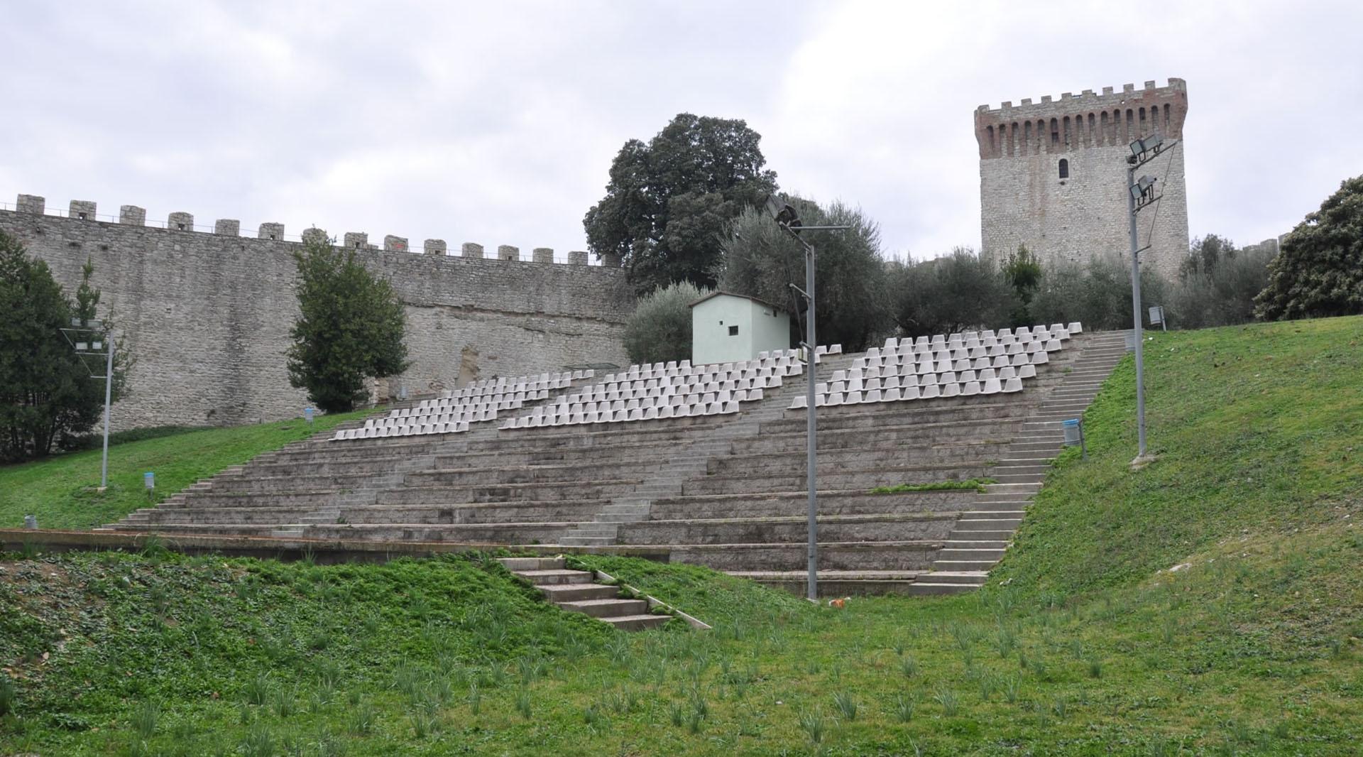 Vue de l'intérieur des murailles de la Rocca del Leone, où l'on peut admirer l'amphithéâtre en plein air, utilisé pour des performances d'artistes nationaux et internationaux, offrant une atmosphère unique dans un cadre historique.
