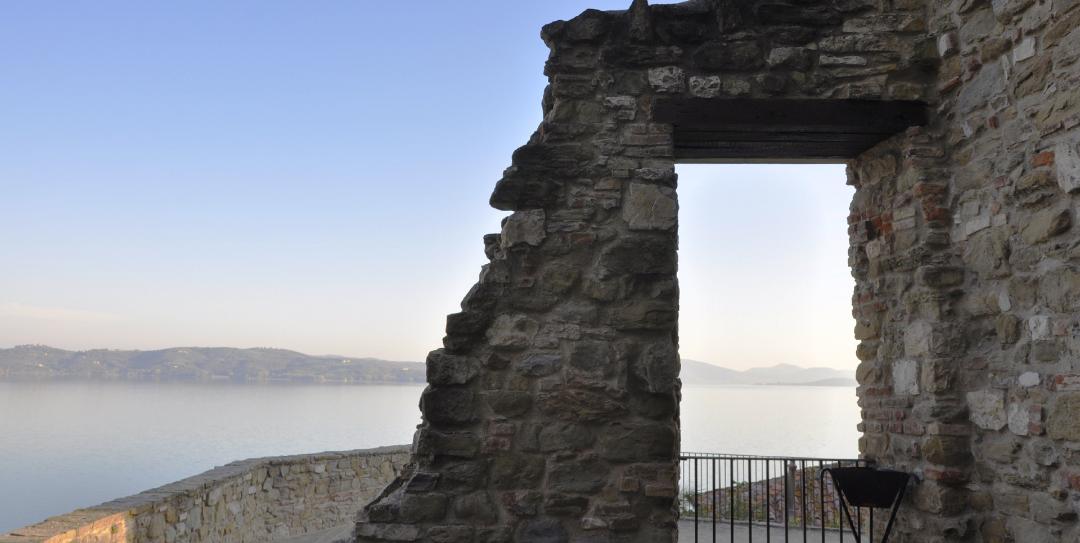 Vista dalla cima della Rocca, dove si apre una feritoia che offre una splendida vista del Lago del Trasimeno sullo sfondo, incorniciato dalle antiche mura.