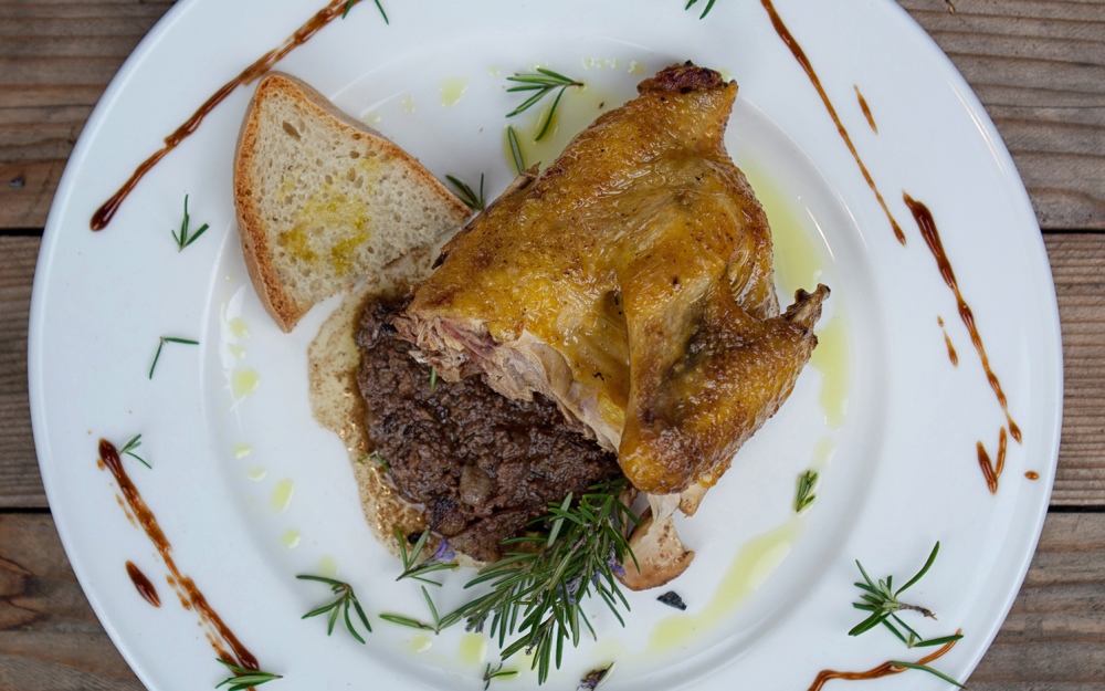 Roast guinea fowl on toasted bread with chicken liver sauce, garnished with rosemary, olive oil and balsamic glaze.