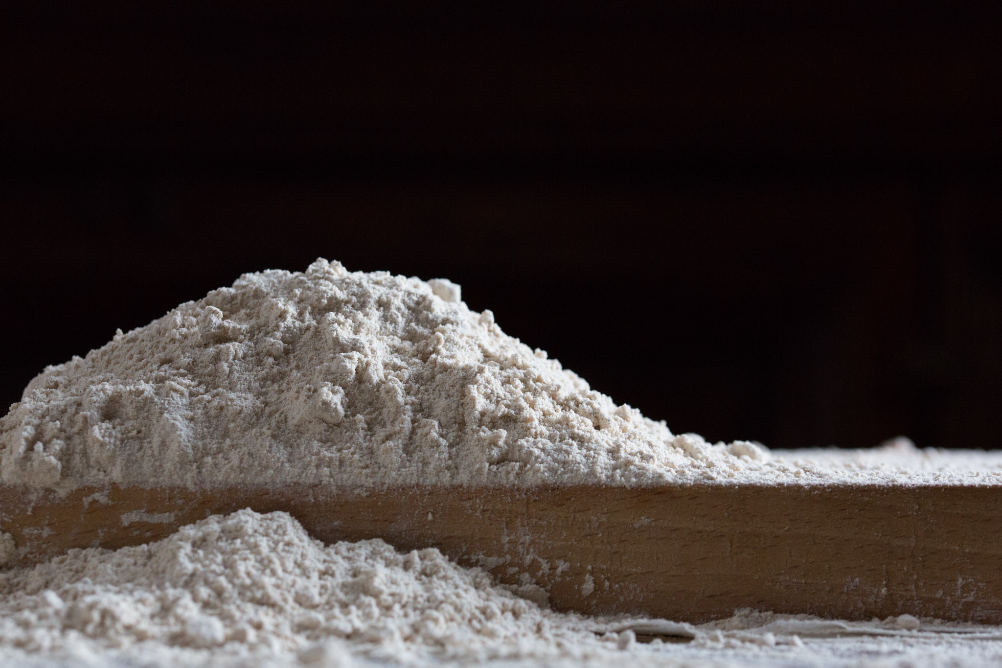Mound of flour on a wooden board, ready for bread making.