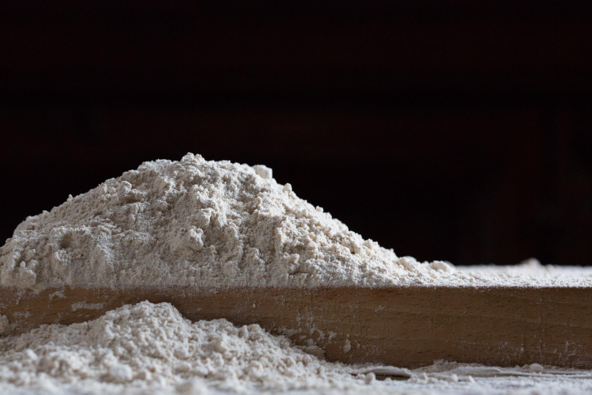 Mound of flour on a wooden board, ready for bread making.