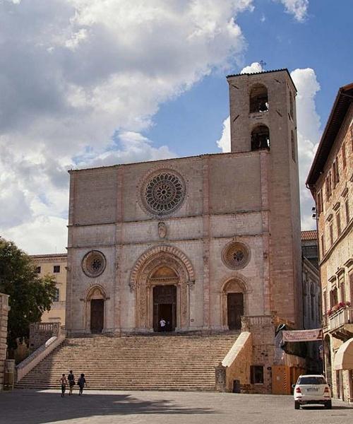 Piazza del Popolo a Todi con il Duomo romanico, la scalinata e la torre campanaria, circondata da palazzi storici.
