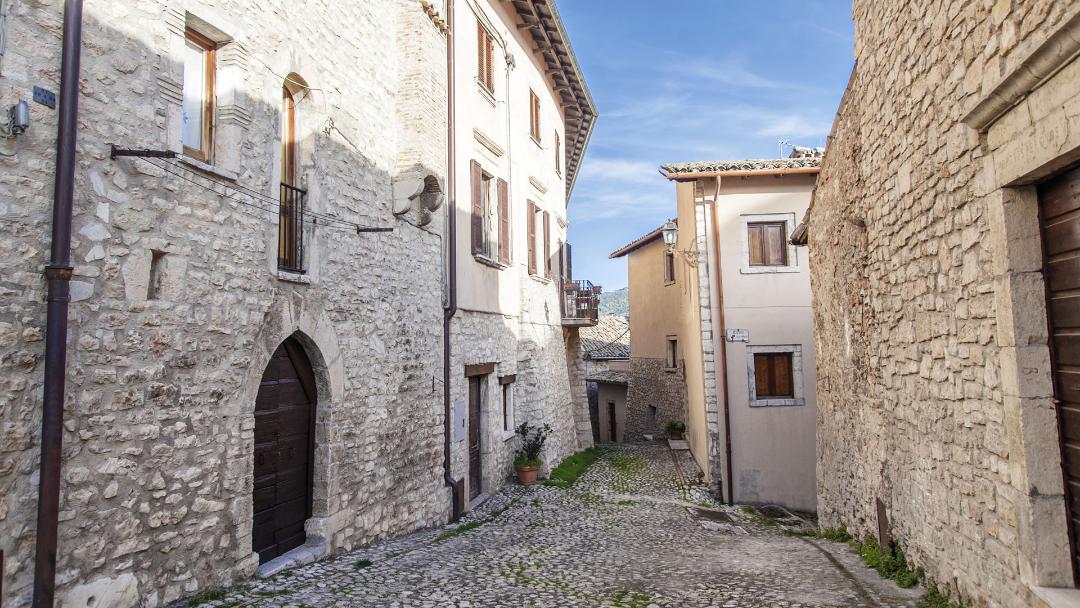 Cobblestone alley in Monteleone di Spoleto, flanked by stone buildings in the historic centre.