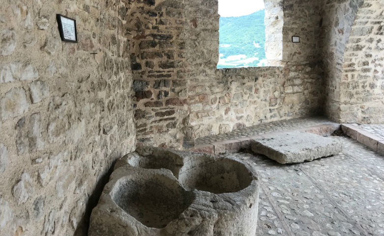 Ancient stone basins inside a historic building in Monteleone di Spoleto, overlooking the surrounding valley.
