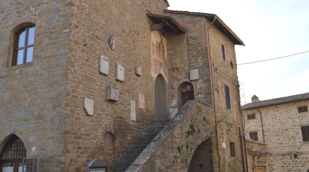 Palazzo del Podestà in Bettona, medieval building with coats of arms on the wall and fresco above the entrance of the external staircase.