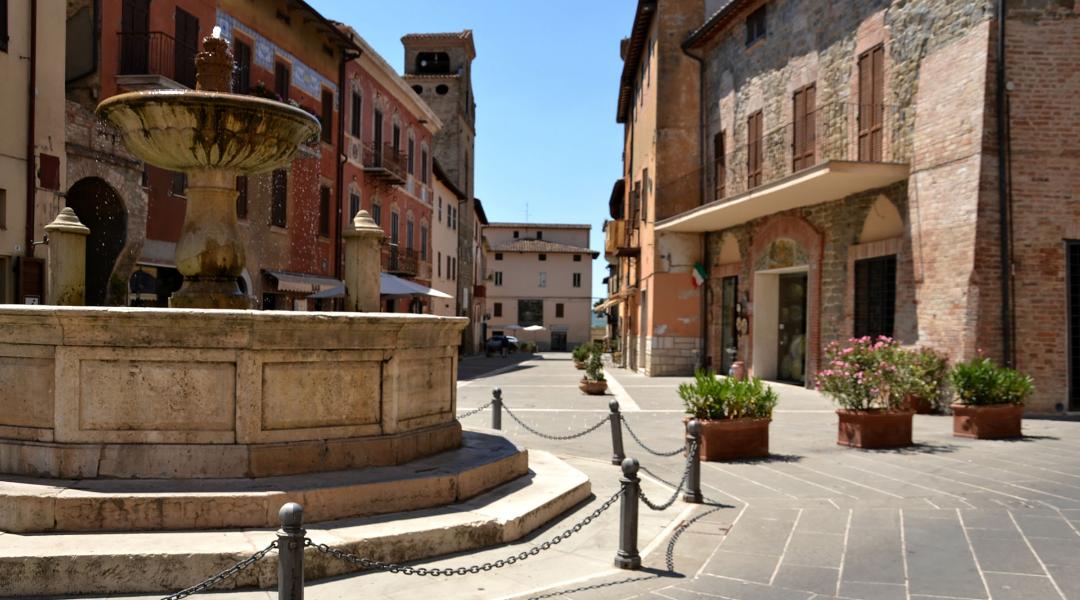 Stone fountain in Deruta’s historic centre, surrounded by historic buildings and cobbled alleys.