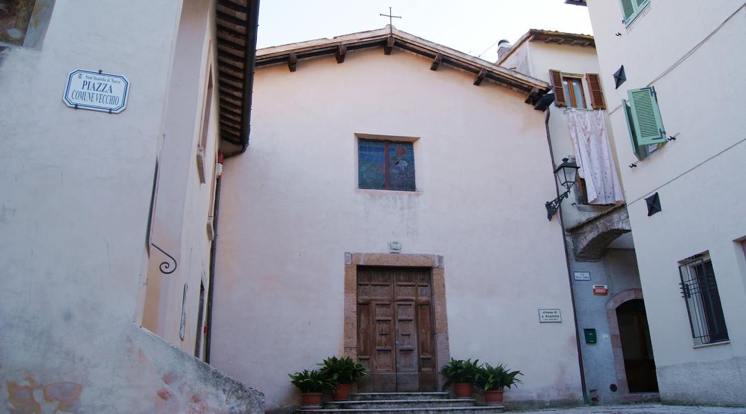 Simple facade of the Church of Sant’Anatolia, located in Piazza Comune Vecchio, framed by historic buildings.