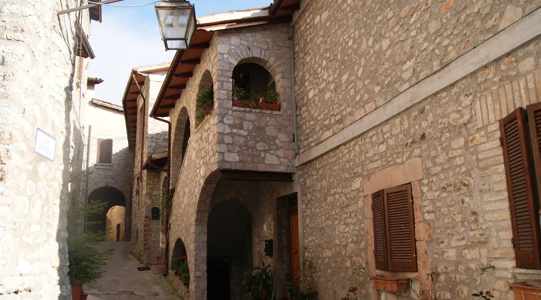 Stone alleys of the village of Sant'Anatolia di Narco, with arches, flowered balconies, and picturesque glimpses among historic houses.