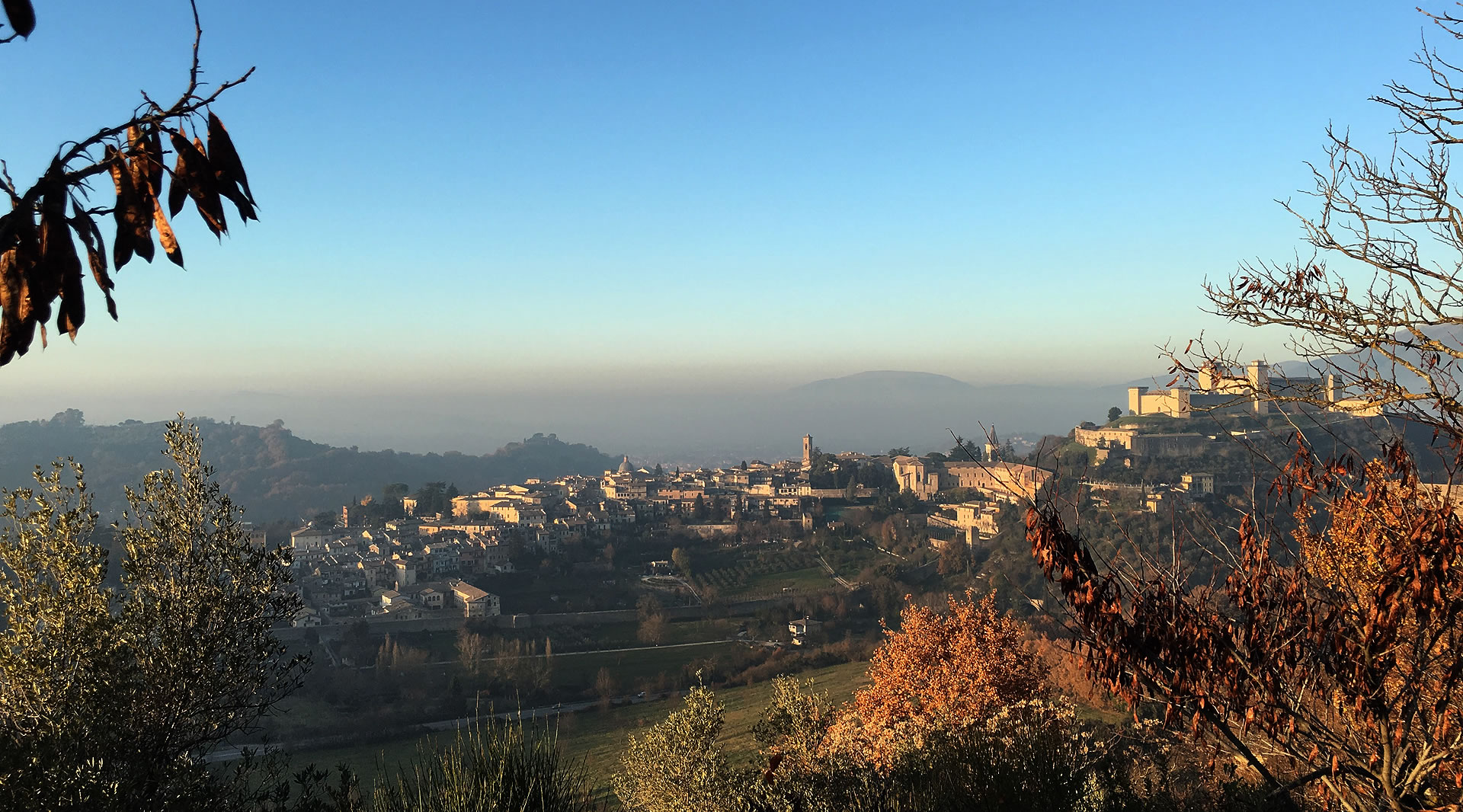 Panoramic view of Spoleto with the Cathedral, the Rocca Albornoziana and historic rooftops nestled among Umbrian hills.