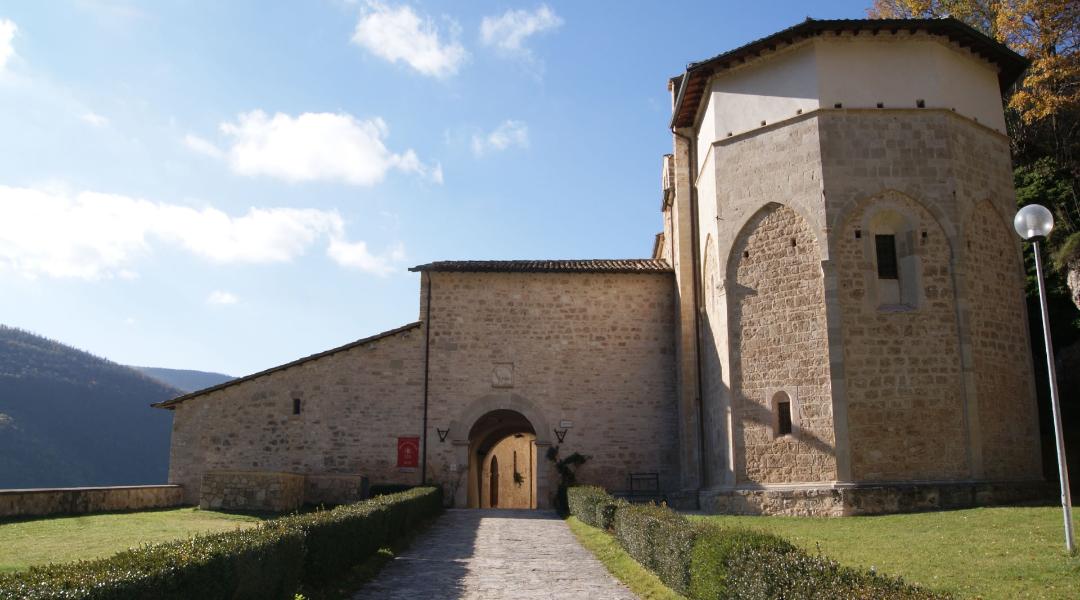 Stone façade of the Abbey of Sant’Eutizio, lit by the sun on a clear day.