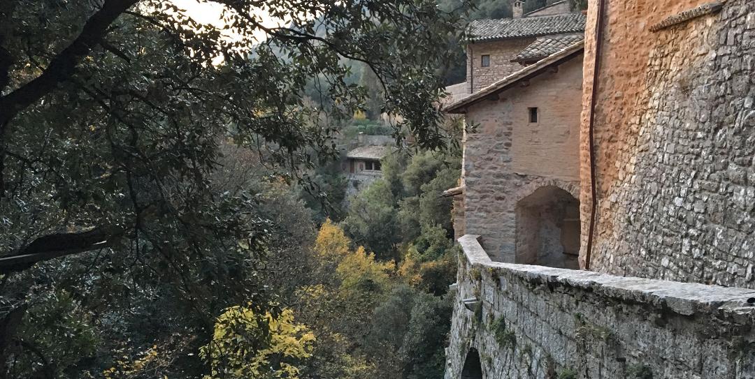 Old stone walls overlooking a lush valley with trees and houses hidden among autumn leaves