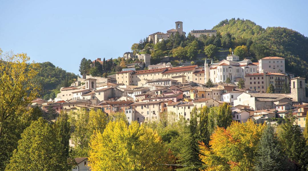 Panoramic view of Cascia, with the historic centre perched among woods and green hills of the Umbrian Apennines.