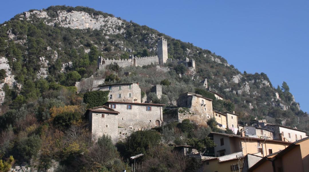 Medieval village of Ferentillo perched on the mountain, with stone houses and a fortified castle amid lush vegetation.