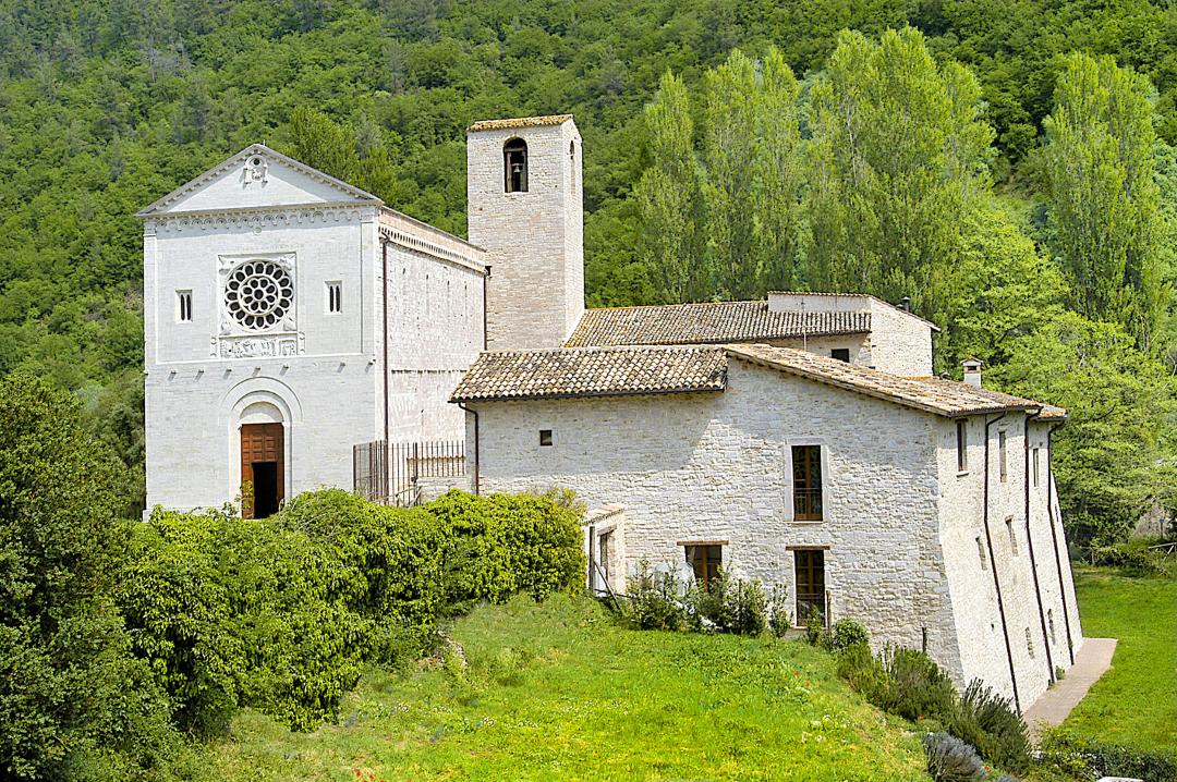 Abbaye des Saints Felice et Mauroimmergée dans la nature au printemps, avec l’église à gauche de l’image, le clocher au centre et les structures de l’ancienne abbaye à droite, aujourd’hui utilisées comme logements.