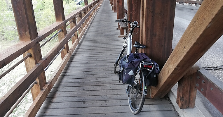 Bicycle resting on the beam of a wooden bridge along a cycle lane