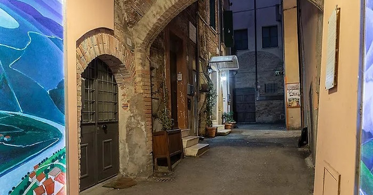 A charming alley with brick arches, historic walls, and colorful artistic decorations, enveloped in an evening atmosphere.