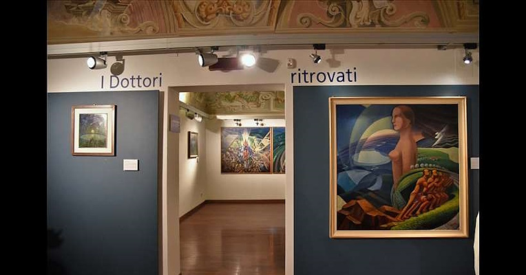 Exhibition hall featuring Futurist artworks, a decorated ceiling, and the inscription “I Dottori ritrovati” (“The rediscovered Dottori artworks”) at Palazzo della Penna.
