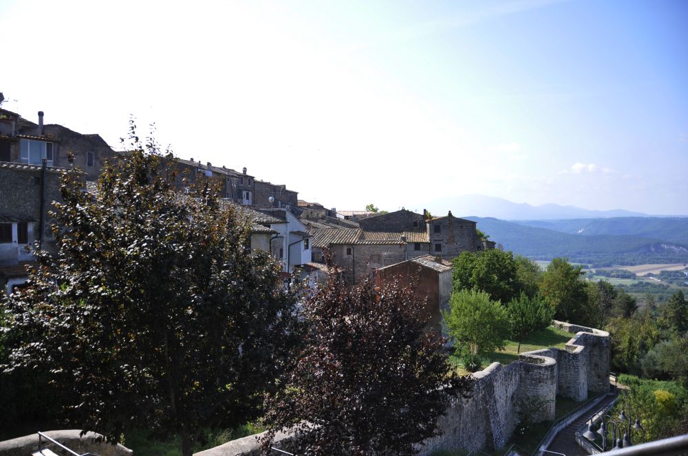 Village of Giove with medieval walls and stone houses, overlooking the Tiber Valley beneath a clear sky.
