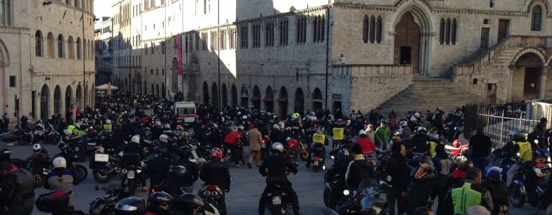 Piazza IV Novembre a Perugia affollata di motociclisti e moto durante un raduno; sullo sfondo, edifici storici.