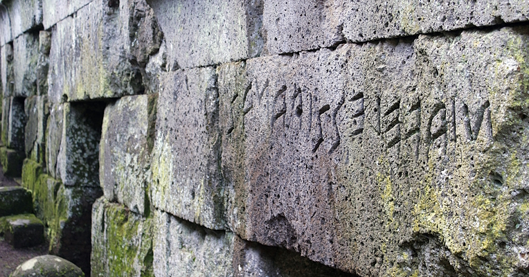 View of a lintel with inscription marking the entrance to a stone tomb in an Etruscan necropolis.