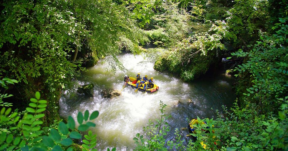 Gelbes Rafting-Schlauchboot inmitten eines Flusses, der durch eine üppige Vegetation fließt