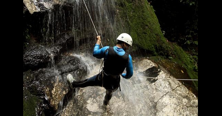 Canyoning durch Abseilen einer Person in einer kleinen Schlucht mit Sicherheitsausrüstung
