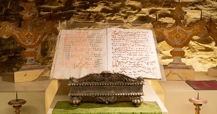 Un ancien pupitre portant des partitions de chants liturgiques, avec des notes bien visibles et des signes d'usure dus au temps.