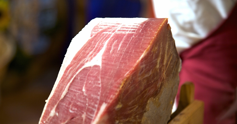 Le Prosciutto di Norcia IGP, tranché à la main, avec la couleurrougecaractéristique de la viande et les marbrures blanches de gras