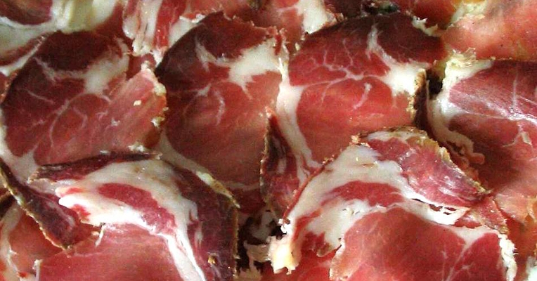 Tranches de capocollo avec la couleur rouge caractéristique de la viande et les veines blanches de la graisse