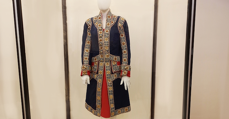 Elegant blue and red livery with gold decorations, displayed in a case in the costume room
