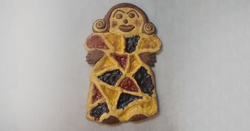Crostata bicolore a forma di figura femminile, decorata con marmellate variopinte e dettagli modellati a mano.