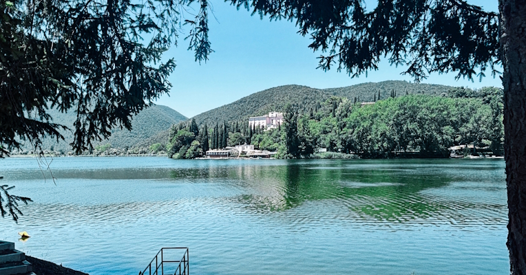 Lac Piediluco avec un escalier et une barque sur la rive. À l'arrière-plan, des collines verdoyantes se reflètent sur la surface du lac