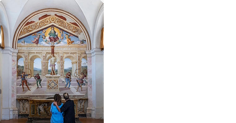 Due donne osservano l'affresco del Martirio di San Sebastiano nella chiesa di San Sebastiano a Panicale.