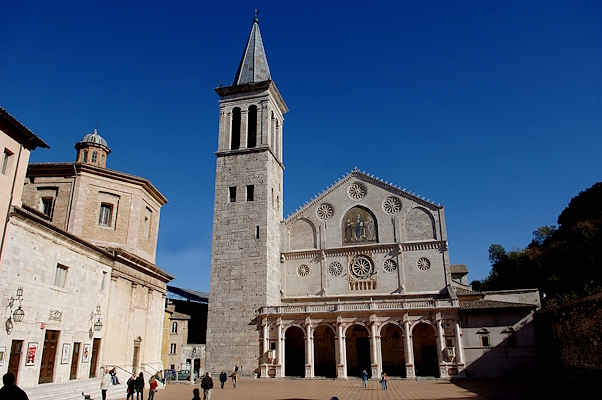 Façade of the Spoleto Cathedral with a colonnaded portico and a tall bell tower to the side