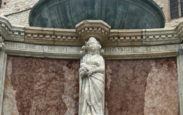 Immagine: Sculpture of the Domina Lacii on the Fontana Maggiore in Perugia, holding some dace fish, with Latin inscriptions on the marble. 