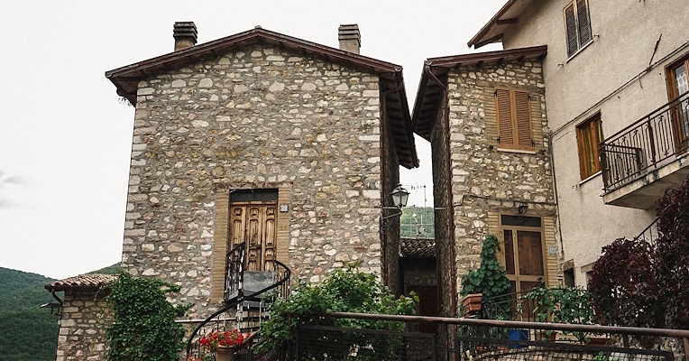 Stone houses with flowered balconies in the historic centre of Poggiodomo