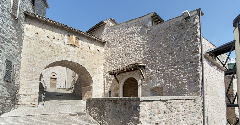 Cobbled alley with a stone arch and historic buildings in the old town of Cerreto di Spoleto