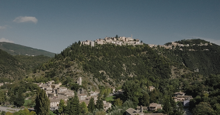 Panoramic view of Cerreto di Spoleto perched on the hill above Borgo Cerreto, both nestled in greenery