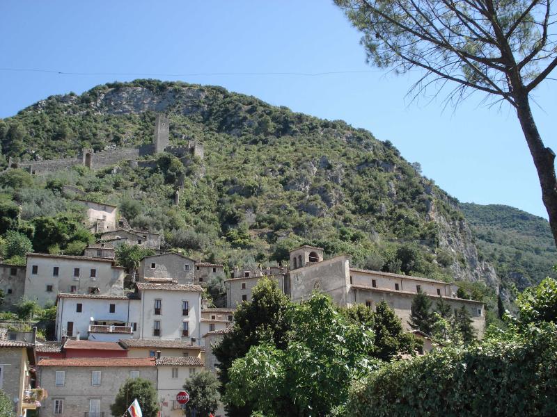 Borgo di Ferentillo ai piedi della montagna, con case in pietra e le rovine del castello che dominano la valle.