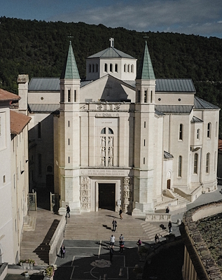 Facade of the Basilica of Saint Rita of Cascia, with twin towers and sculpted portal, overlooking a square.
